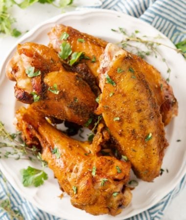 air fryer turkey wings on a plate with herbs and seasoning