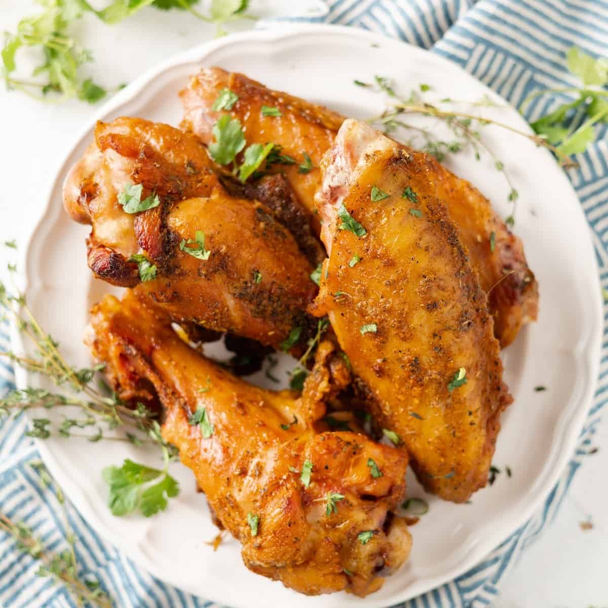 air fryer turkey wings on a plate with herbs and seasoning