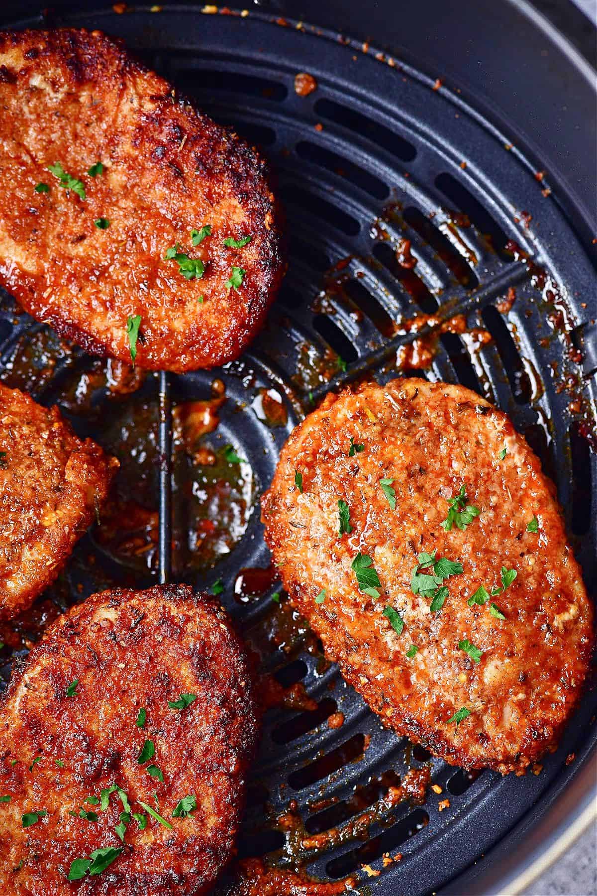 close up photo of crispy parmesan crusted pork chops in an air fryer basket