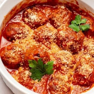 cooked air fryer frozen meatballs in a white bowl with parsley and red sauce