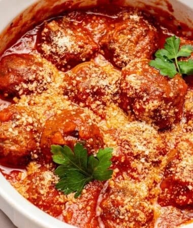 cooked air fryer frozen meatballs in a white bowl with parsley and red sauce