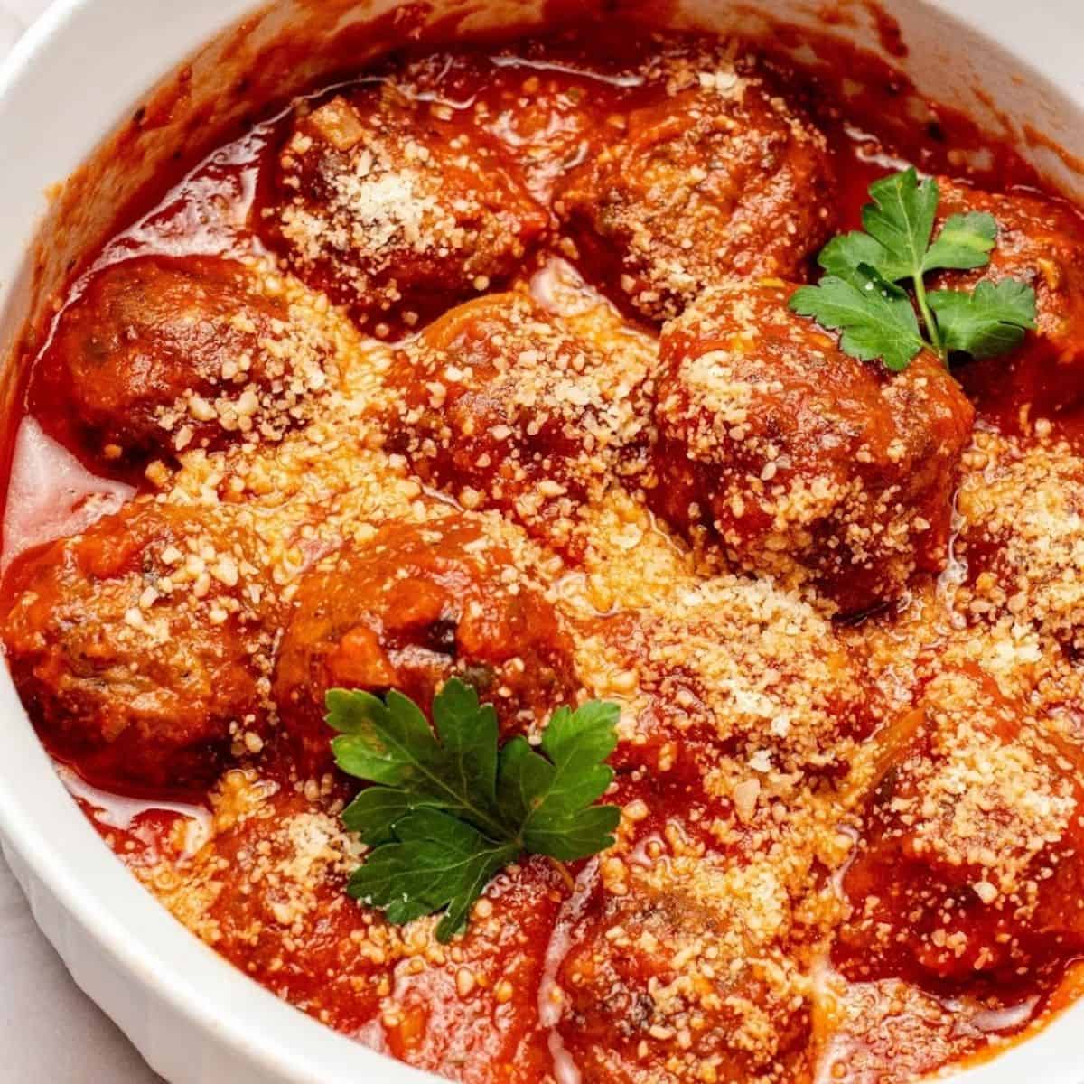 cooked air fryer frozen meatballs in a white bowl with parsley and red sauce
