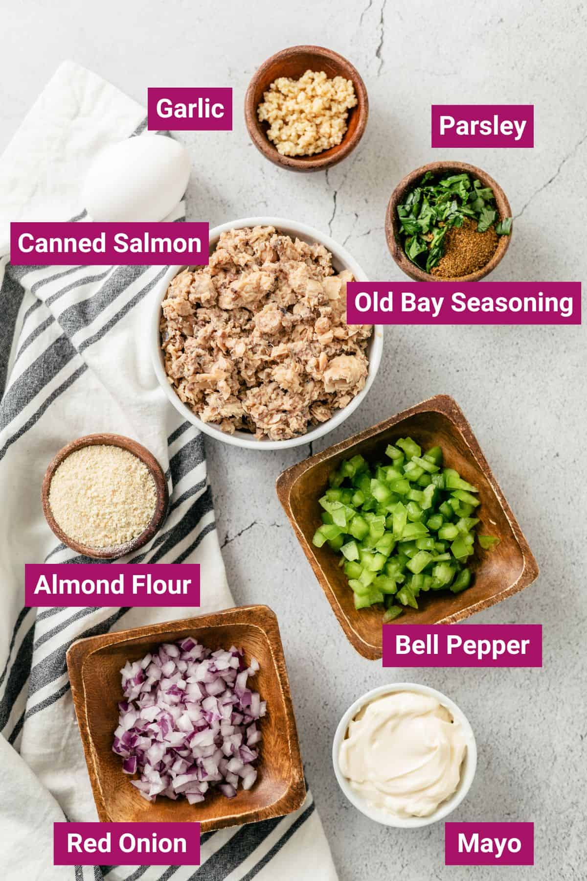ingredients needed to make salmon patties in the air fryer: Parsley, canned salmon, old bay seasoning, almond flour, garlic, mayo, bell pepper, red onion on separate bowls
