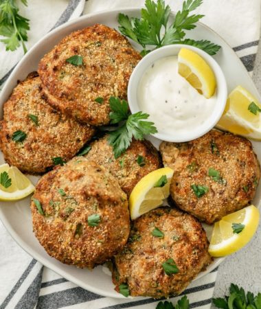 a plate of ninja air fryer salmon patties with tartar sauce and lemon wedges