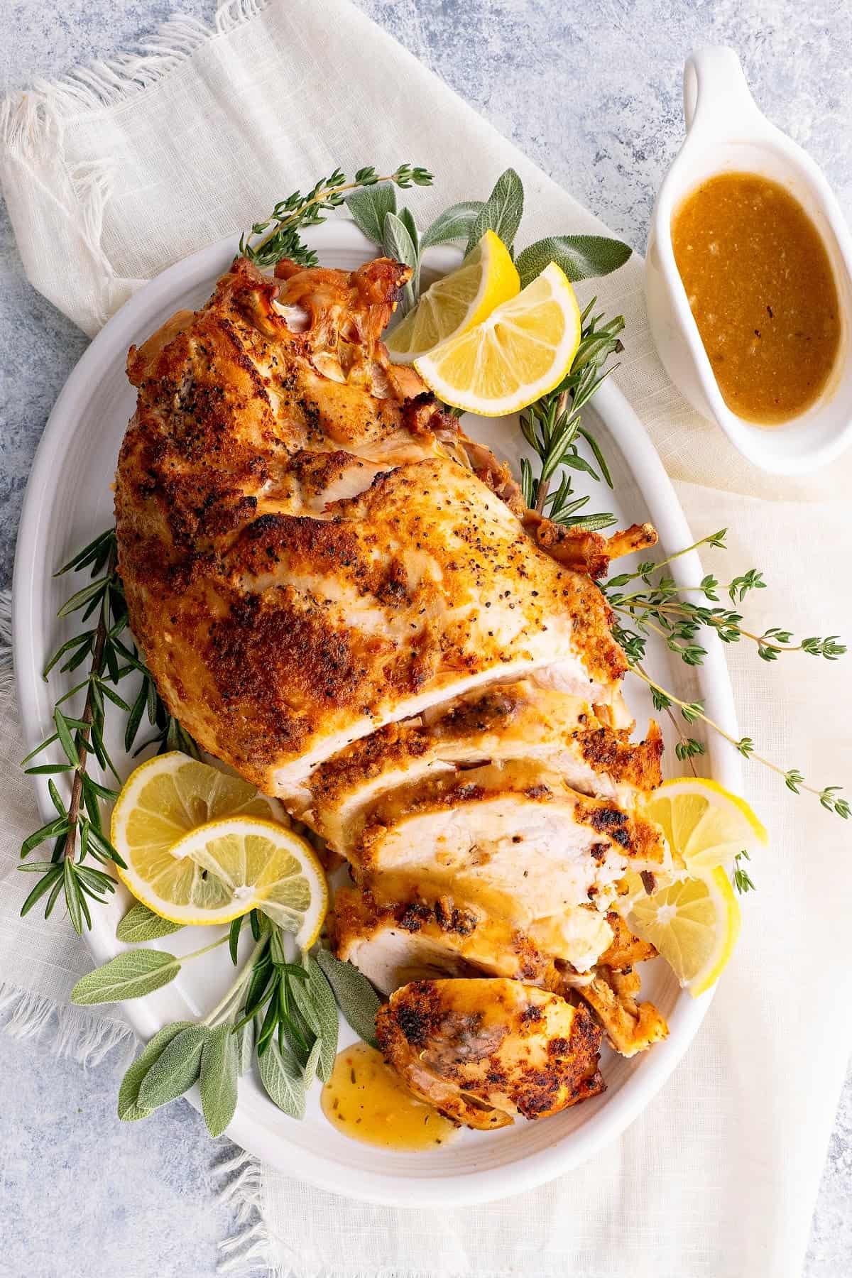 pressure cooker turkey breast on a plate with lemon slices, turkey gravy and fresh herbs