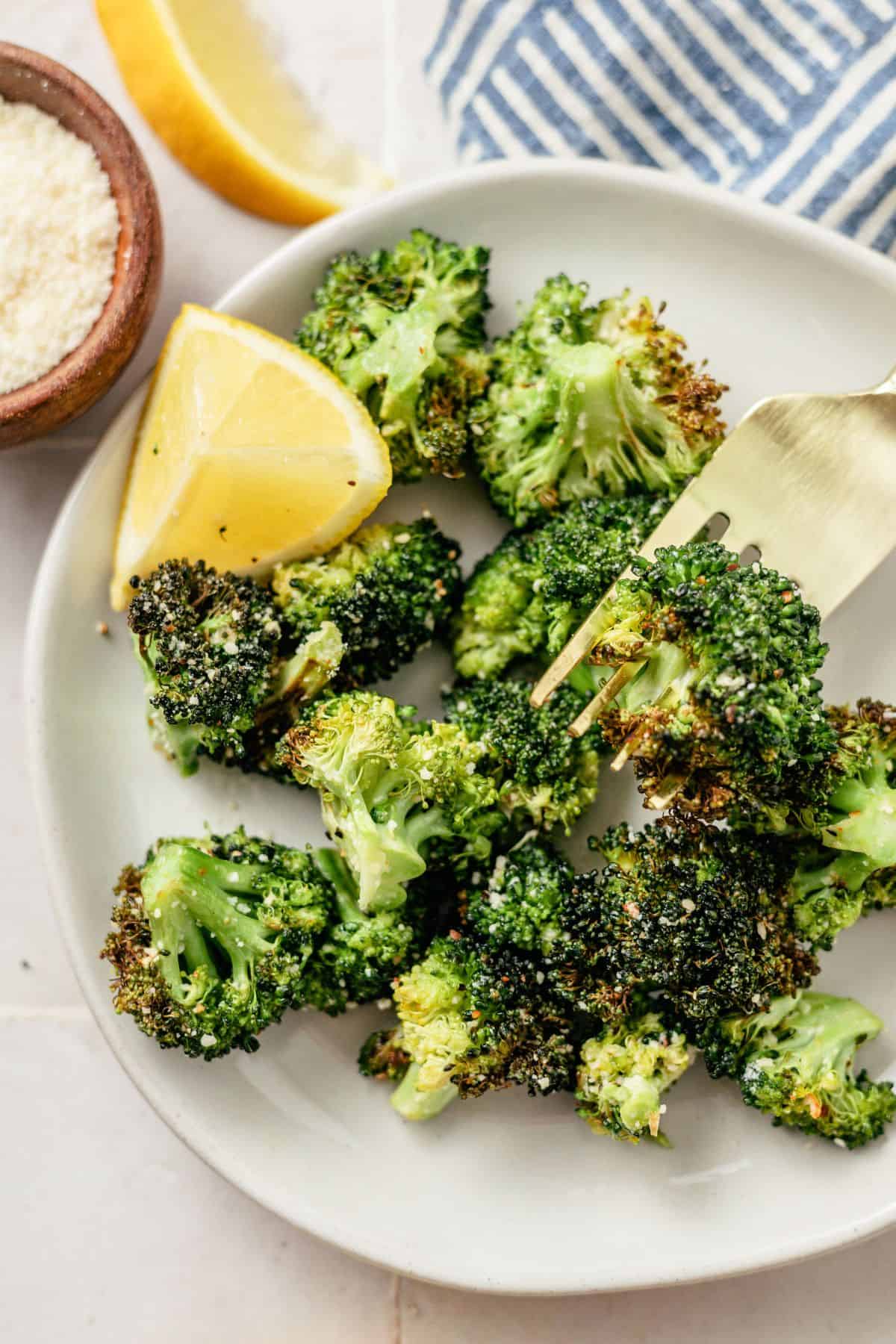 using a fork to get some ninja air fryer broccoli from the plate