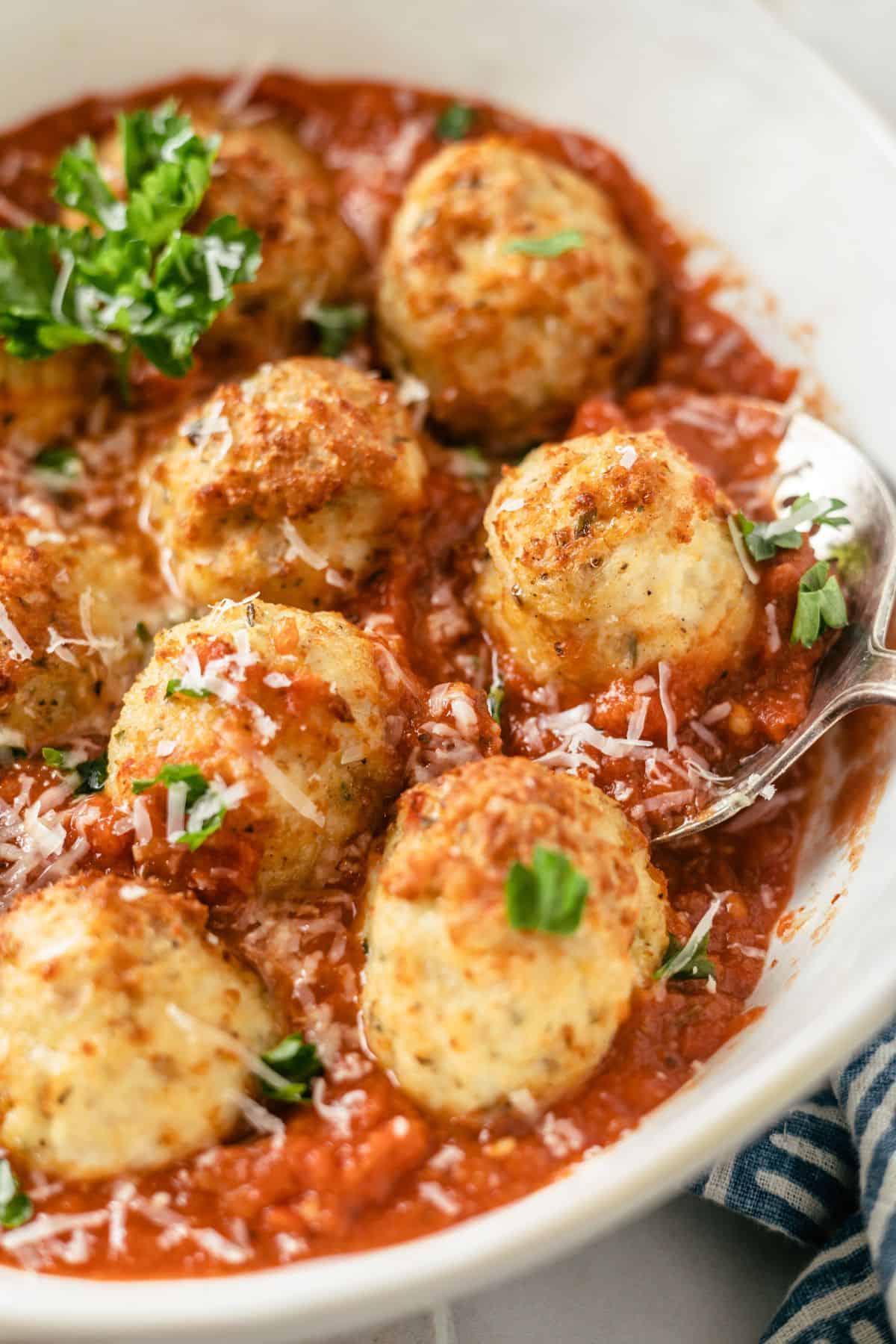 Delectably seasoned and cooked ground chicken meatballs, enticingly presented with marinara sauce, fresh parsley and shaved parmesan cheese in a generous bowl