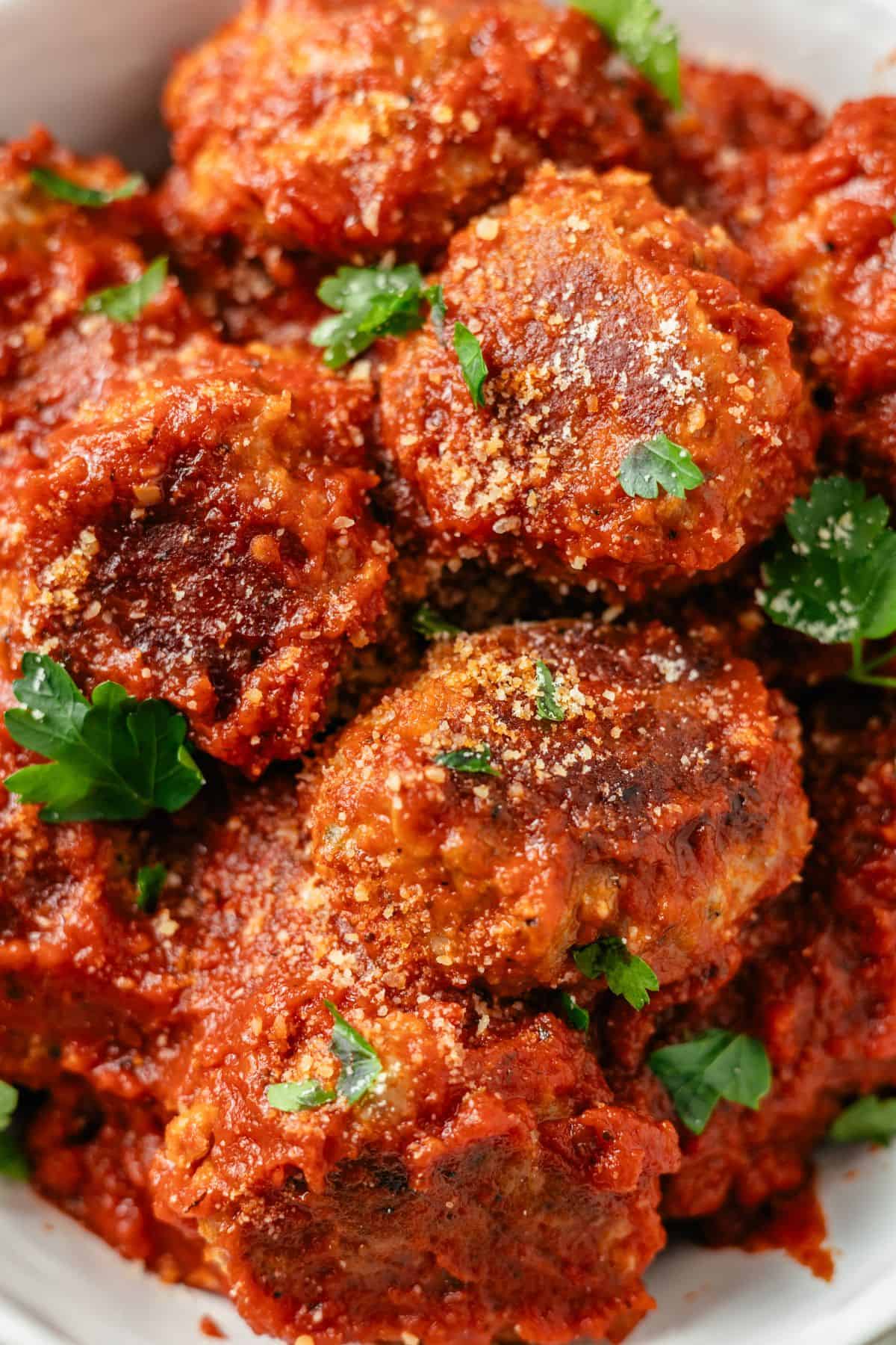 Close-up of succulent meatballs in a bowl, generously crowned with a sprinkle of grated Parmesan, inviting a mouthwatering feast for the eyes