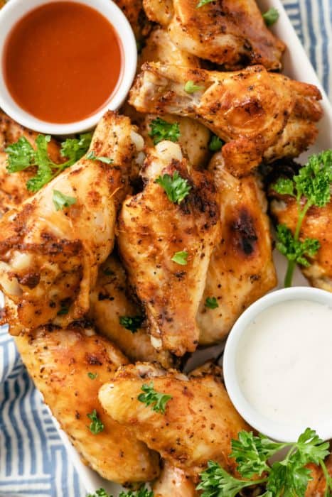 Slow Cooker Chicken Wings garnished with fresh parsley, accompanied by flavorful dips on the side