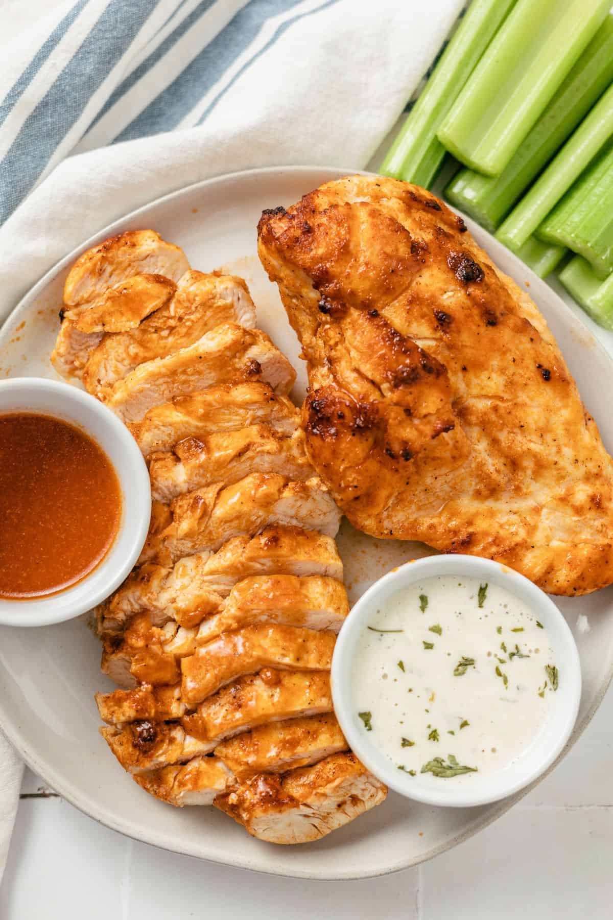 buffalo chicken breasts served with celery sticks, dipping sauce, and blue cheese dressing