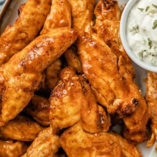 plated air fryer buffalo chicken tenders with a cup of blue cheese dressing