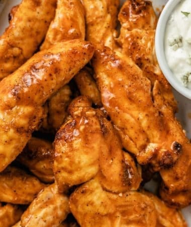 plated air fryer buffalo chicken tenders with a cup of blue cheese dressing