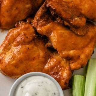air fryer buffalo chicken thighs with dipping sauce and fresh celery sticks for crunch