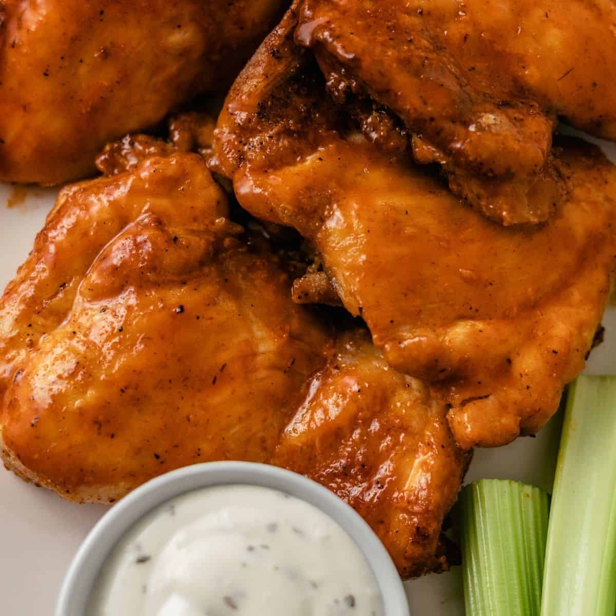 air fryer buffalo chicken thighs with dipping sauce and fresh celery sticks for crunch
