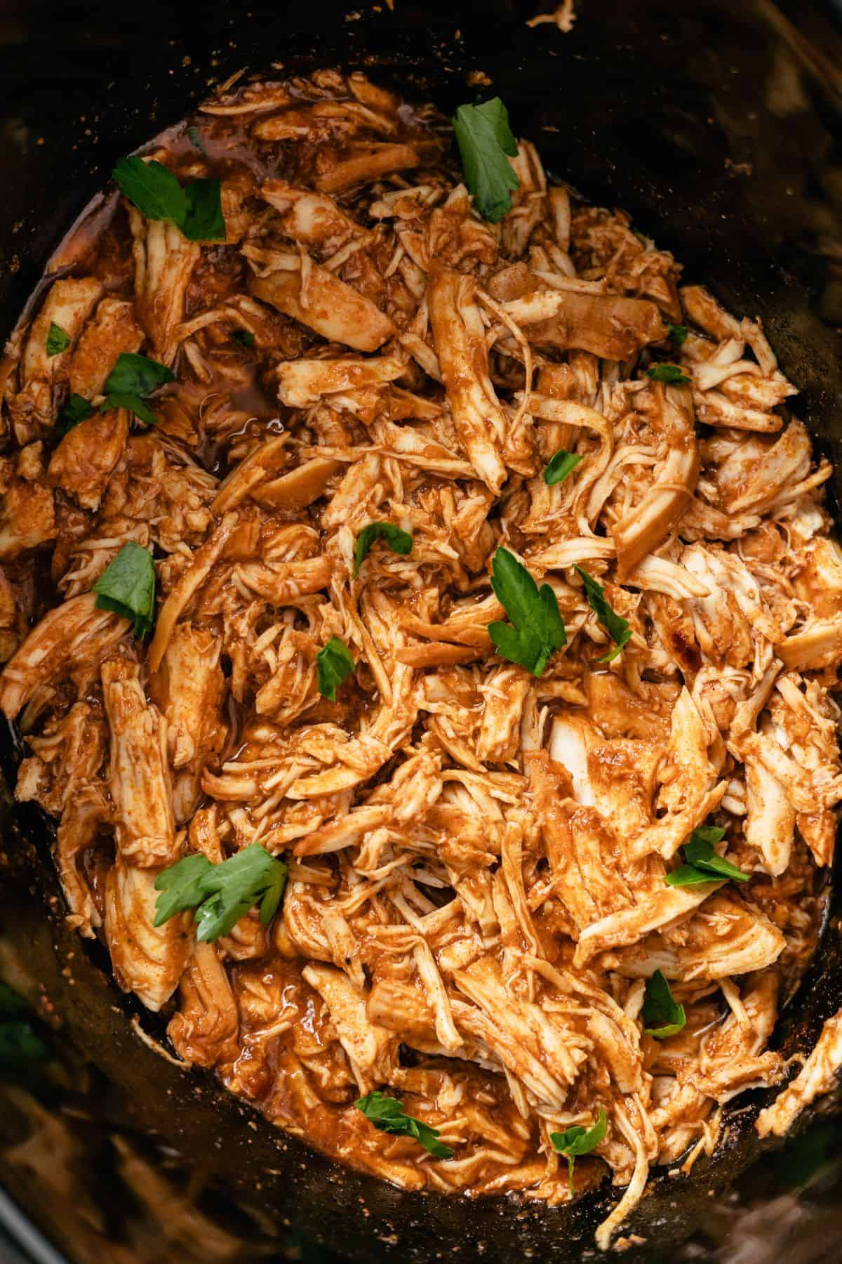 BBQ chicken in a crockpot topped with fresh parsley
