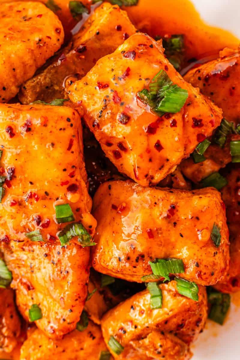 Spicy-sweet hot honey salmon bites served in a white bowl with green onions
