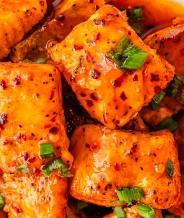 Hot honey-glazed salmon bites in a bowl, ready to serve with green onions on top