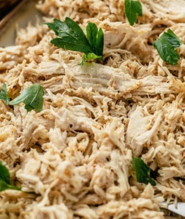 shredded chicken topped with fresh parsley on a serving platter