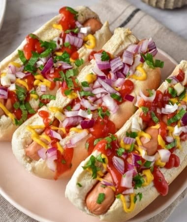 hot dog sandwiches with red onion and sauce, ready to eat