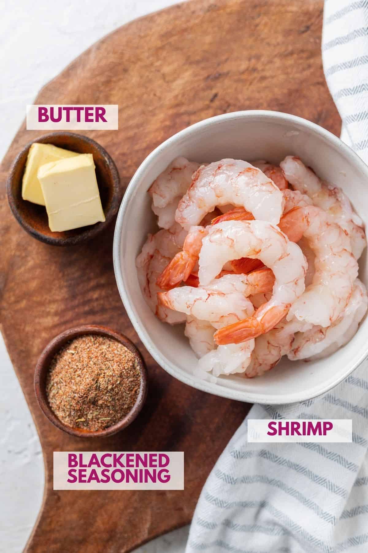 ingredients to make blackened shrimp in a cast iron skillet on a wooden board