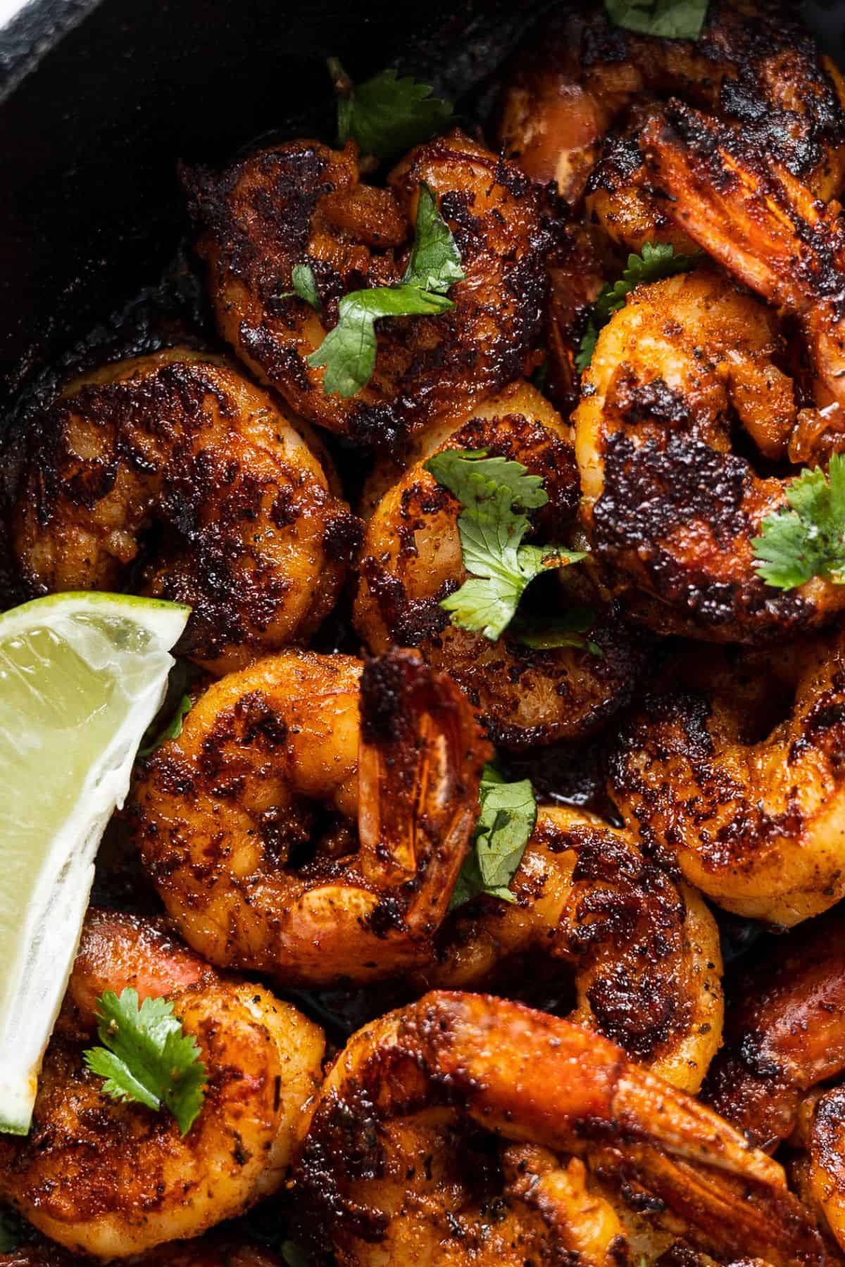 Finished blackened shrimp in a skillet with fresh herbs and citrus