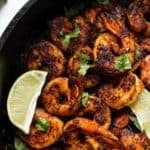 Cooked blackened shrimp with fresh parsley and lemon wedges in a pan