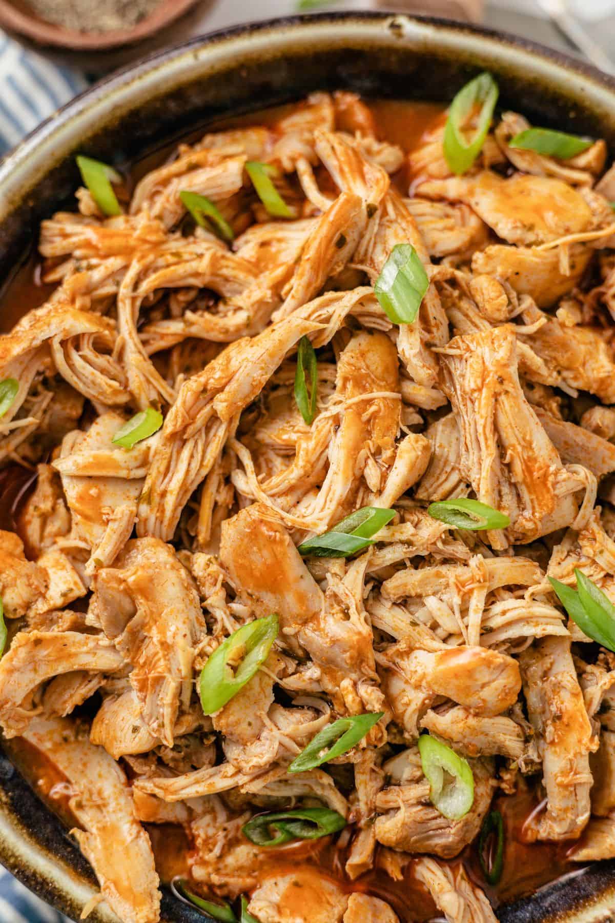 Instant Pot shredded chicken tossed in spicy buffalo sauce in a meal prep bowl