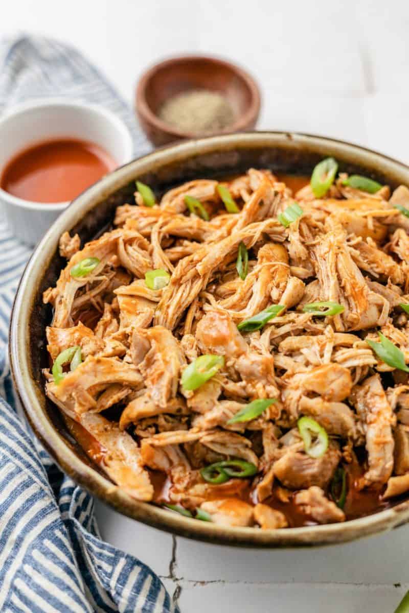 a bowl of pressure cooker buffalo chicken topped with sliced green onions