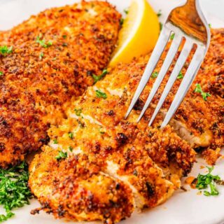 Homemade Parmesan crusted chicken breast ready to serve on white plate