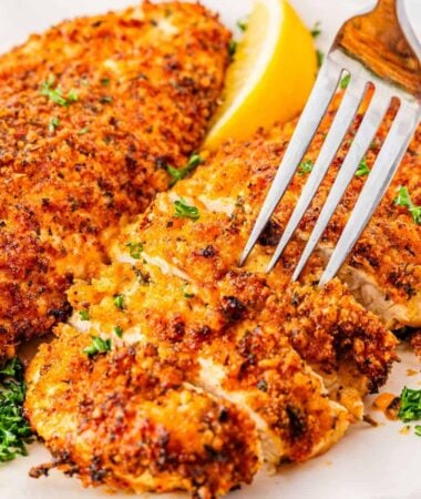 Homemade Parmesan crusted chicken breast ready to serve on white plate