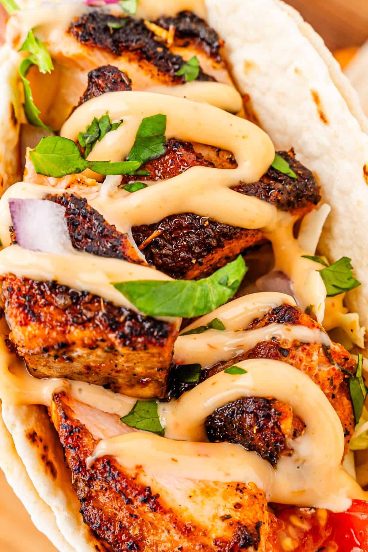 Salmon tacos served with fresh vegetables and rich bang bang sauce