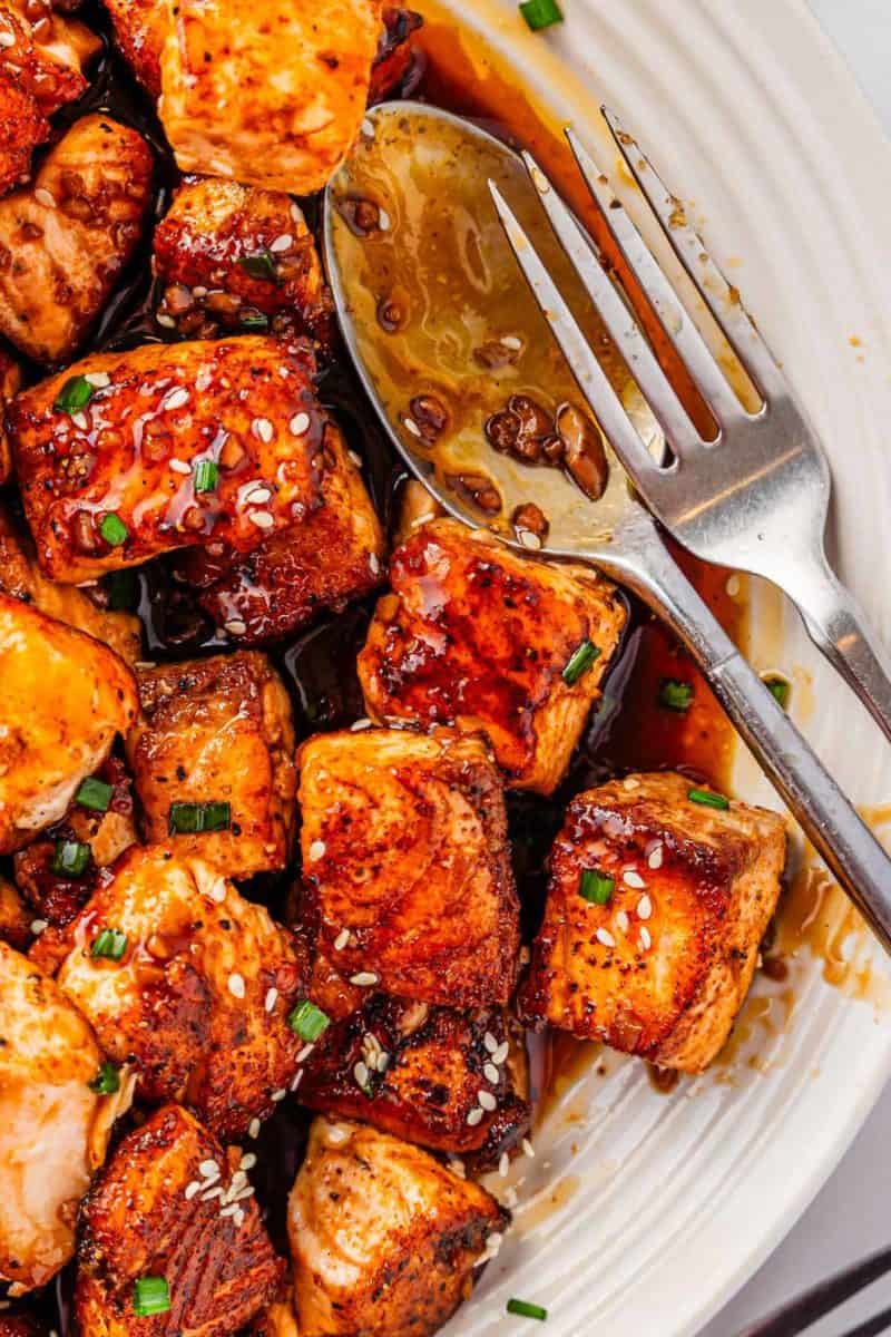 Weeknight teriyaki salmon bites plated with chopped chives and sesame seeds