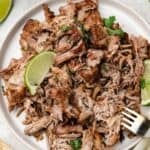 Plated pork carnitas with crispy edges, slow-cooked in citrus, garlic, and spices