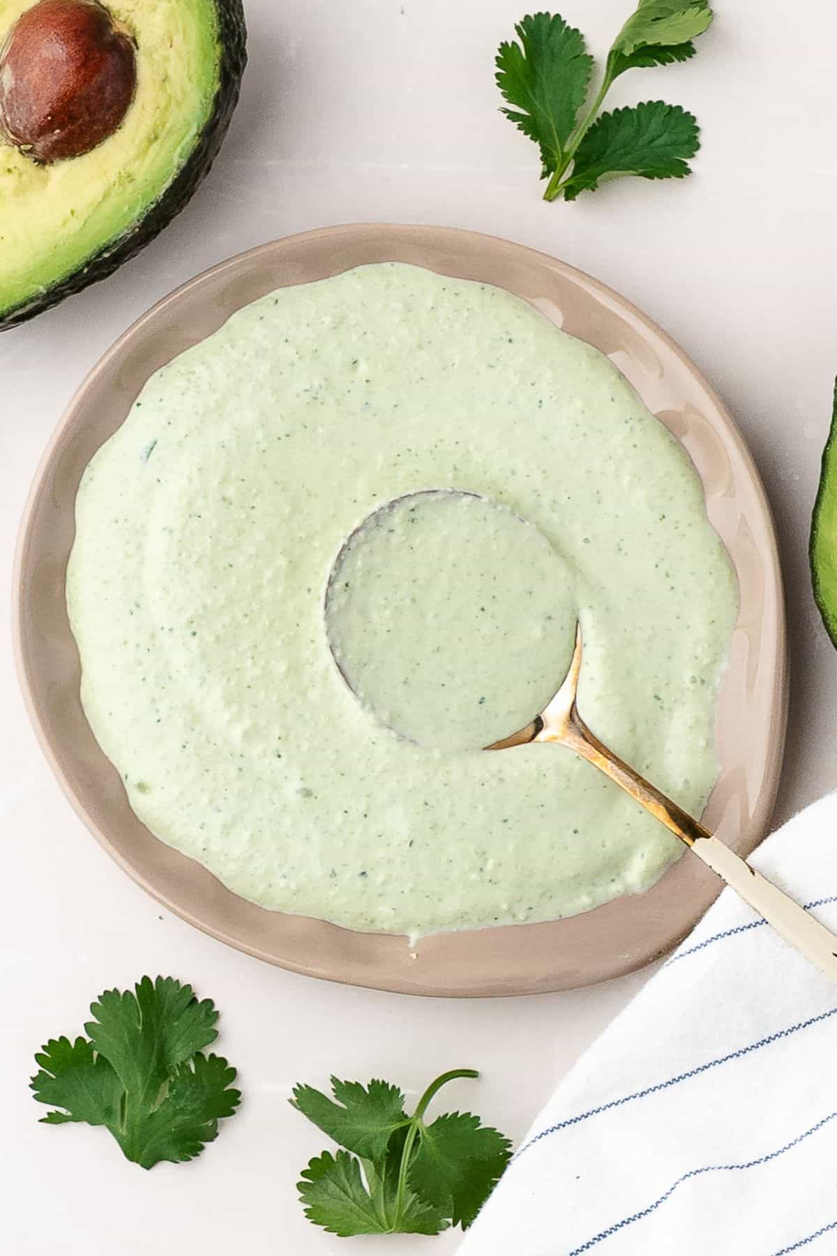 Creamy avocado sauce in a bowl with a spoon, perfect for steak, chicken, or shrimp tacos