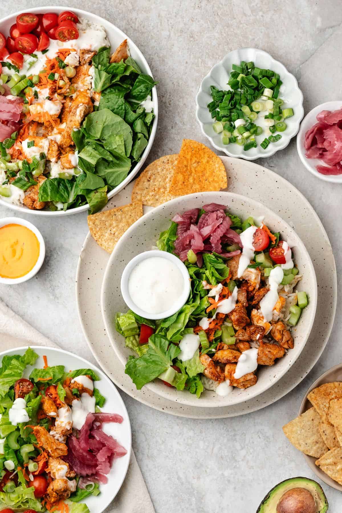 Spicy chicken and warm rice bowls layered with lettuce, tomatoes, and ranch drizzle