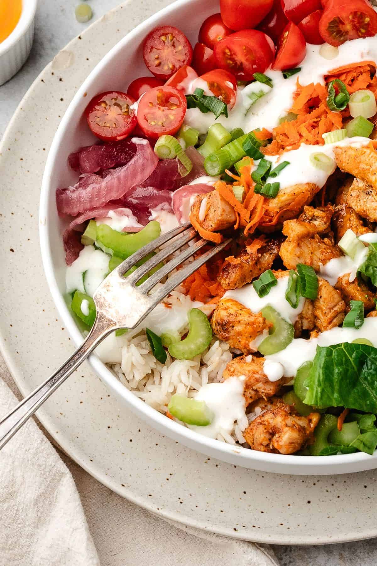 Flavorful buffalo chicken bowl served with warm rice and colorful veggies