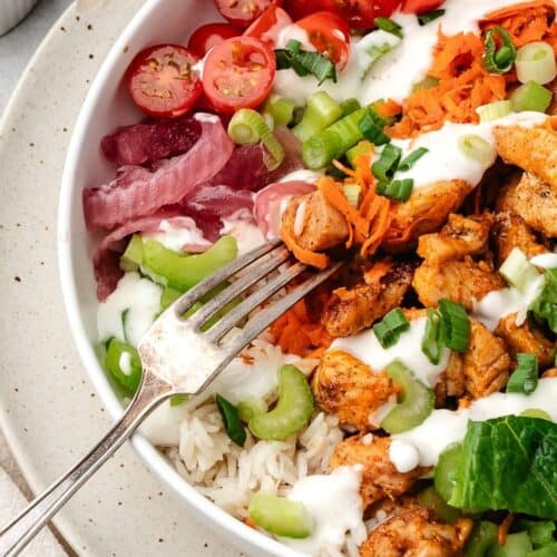 Homemade buffalo chicken bowl layered with rice, veggies, and melted cheese