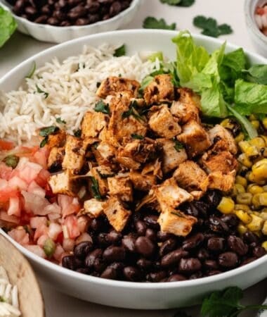 Smoky chipotle chicken pieces layered over a bed of rice and vegetables