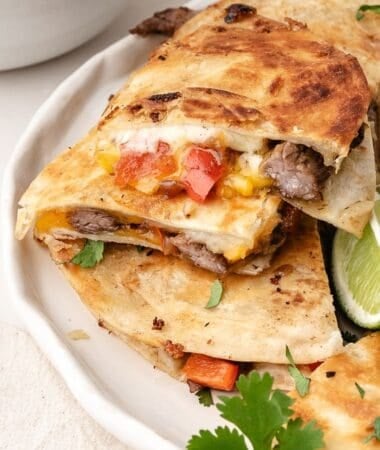 Plated steak quesadilla triangles with tender steak, sautéed vegetables, and melted cheese