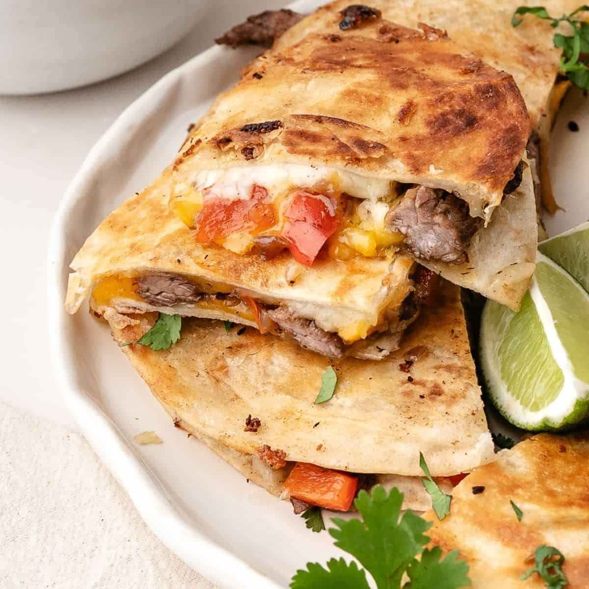 Plated steak quesadilla triangles with tender steak, saut&eacute;ed vegetables, and melted cheese