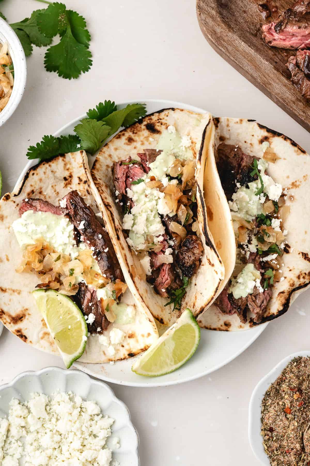 Warm tortillas filled with juicy skirt steak, charred onions, and avocado cream sauce