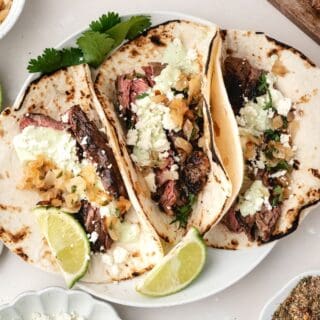 Juicy marinated steak sliced and served in tortillas with avocado cream and lime wedges