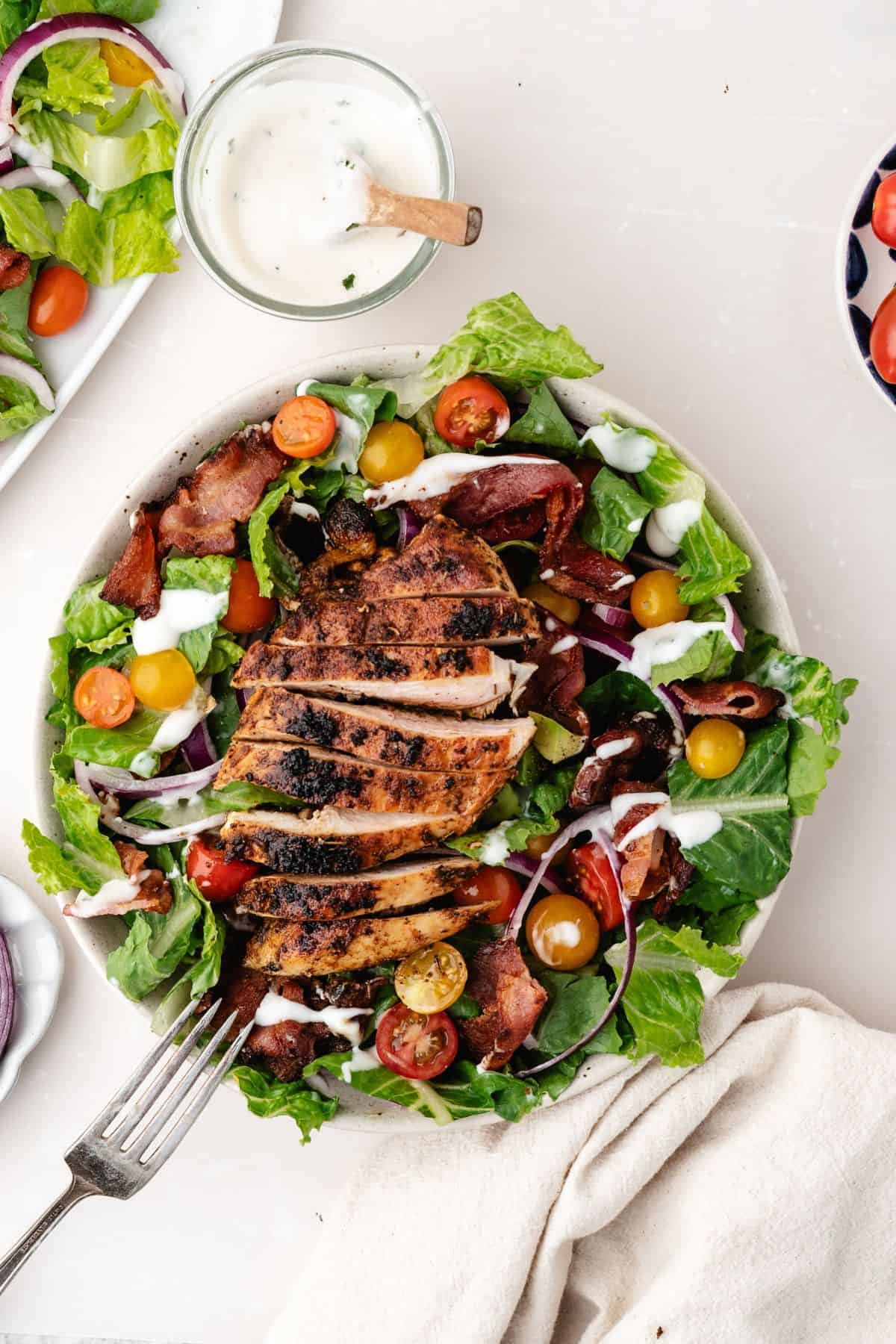 a blt chicken salad with sliced chicken breast on top