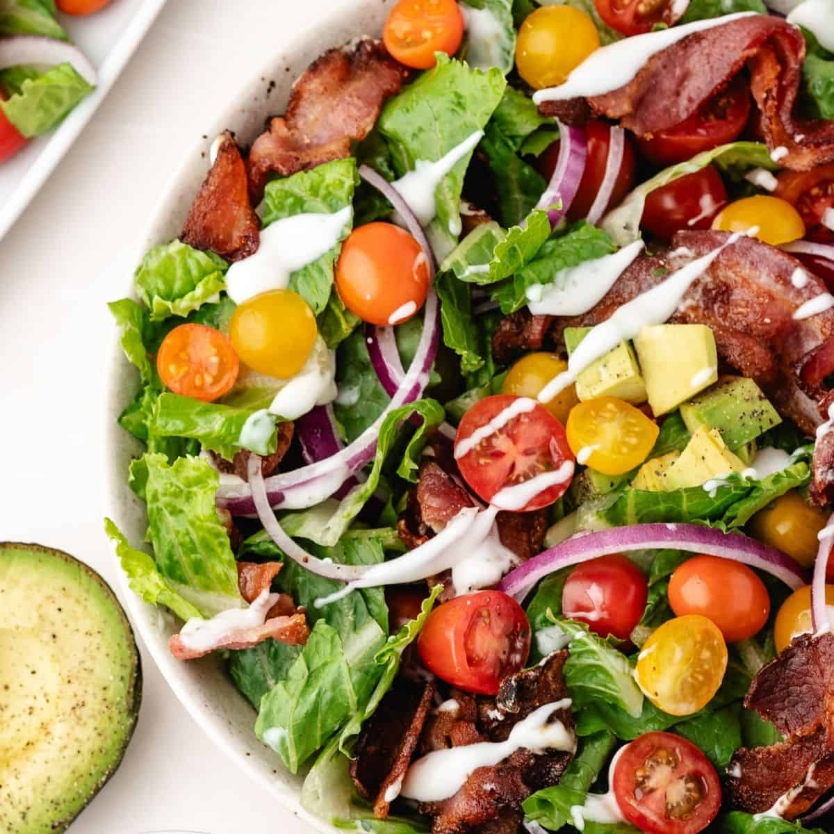 bacon, lettuce and tomato salad with avocado and ranch dressing in a bowl