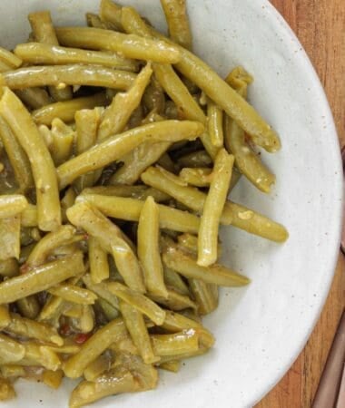Canned green beans cooked with garlic, butter, and salt on a plate