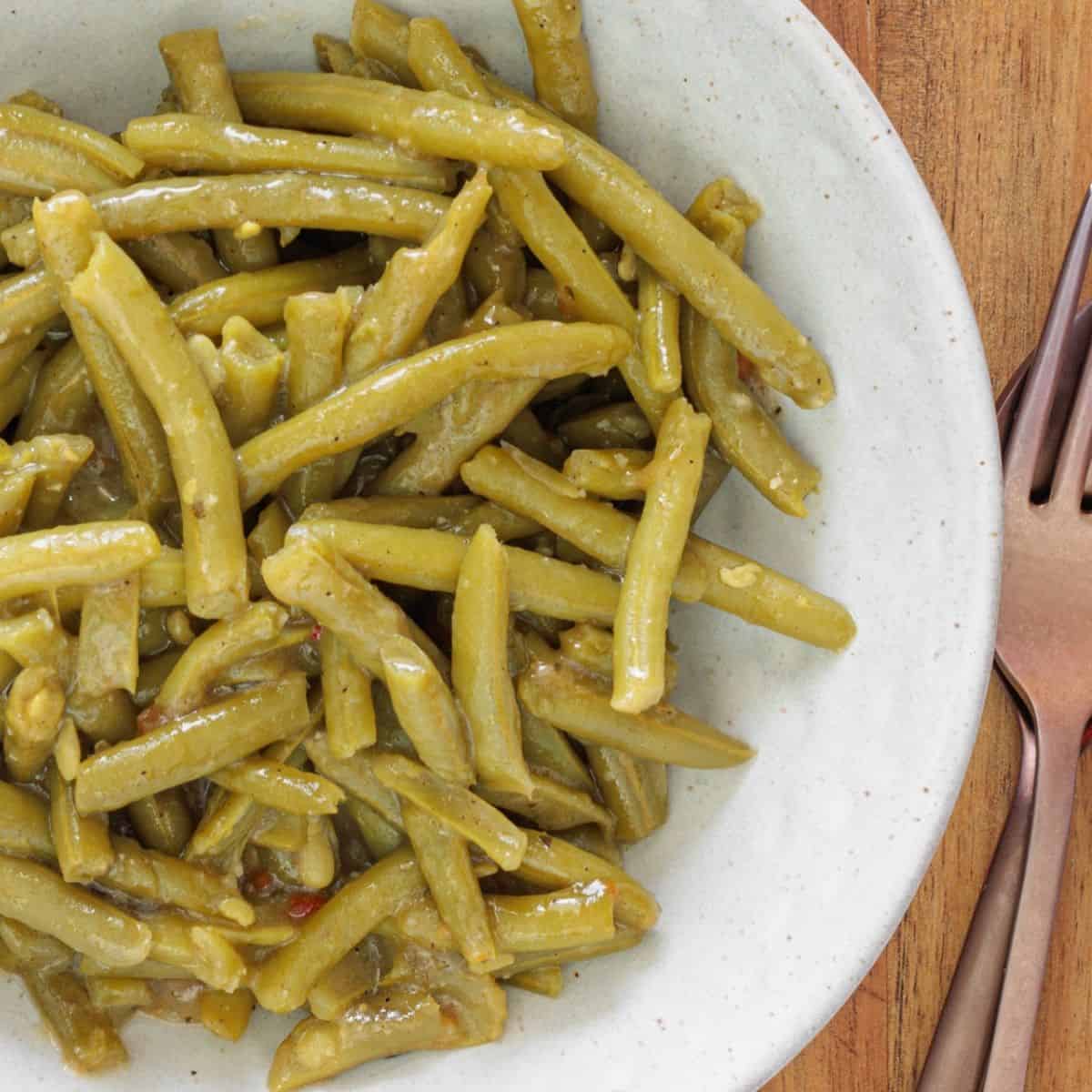 Canned green beans cooked with garlic, butter, and salt on a plate