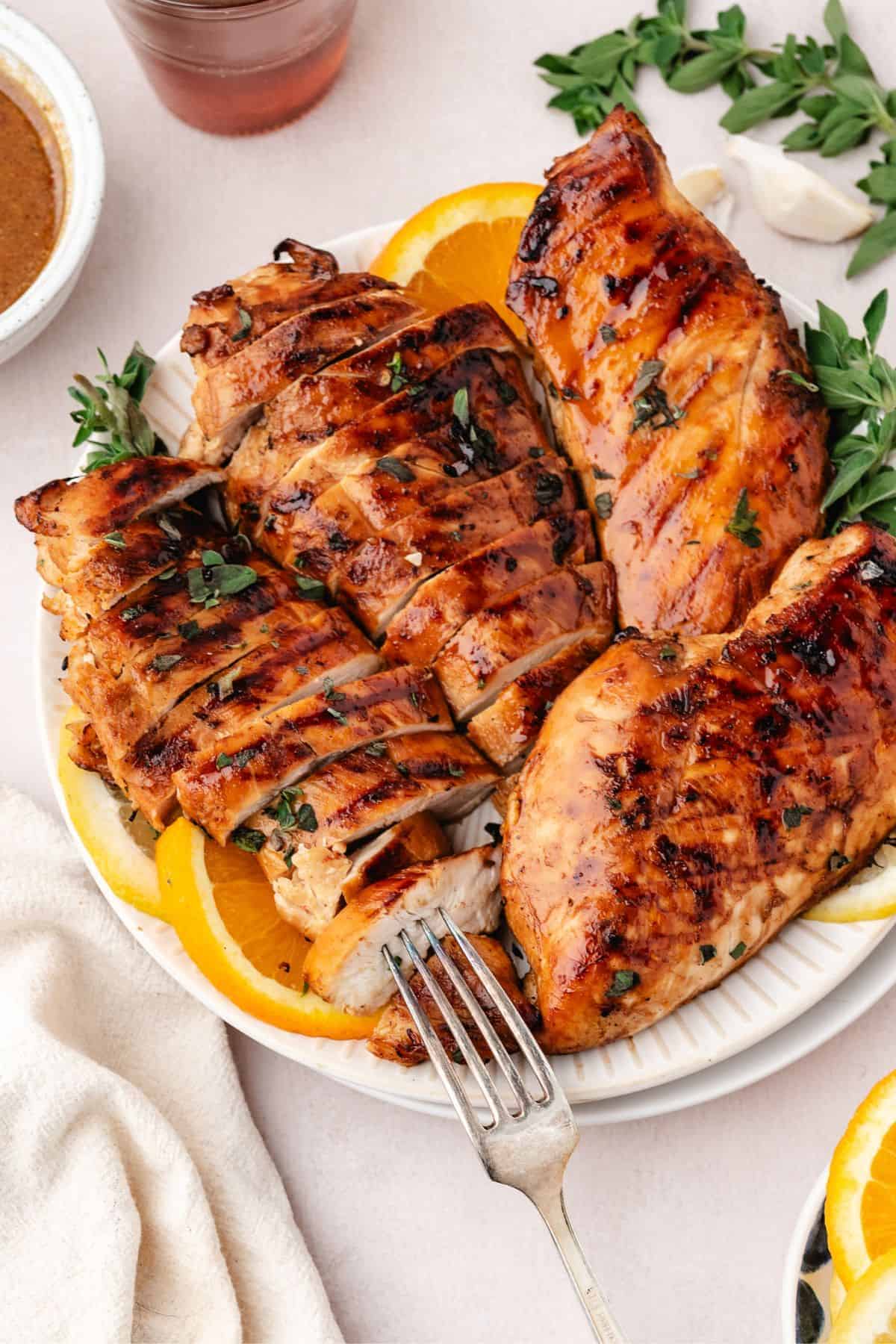 Seasoned chicken breasts in marinade displayed with fresh lemon wedges