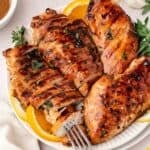 Marinated chicken breasts plated with fresh lemon slices on the side