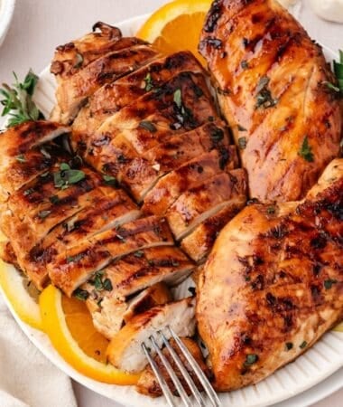 Marinated chicken breasts plated with fresh lemon slices on the side