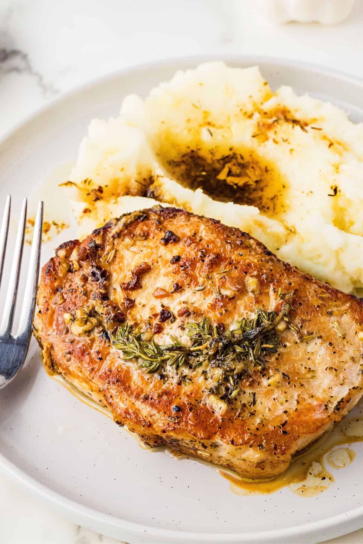 Garlic butter pork chops with crispy edges and juicy center paired with mashed potato